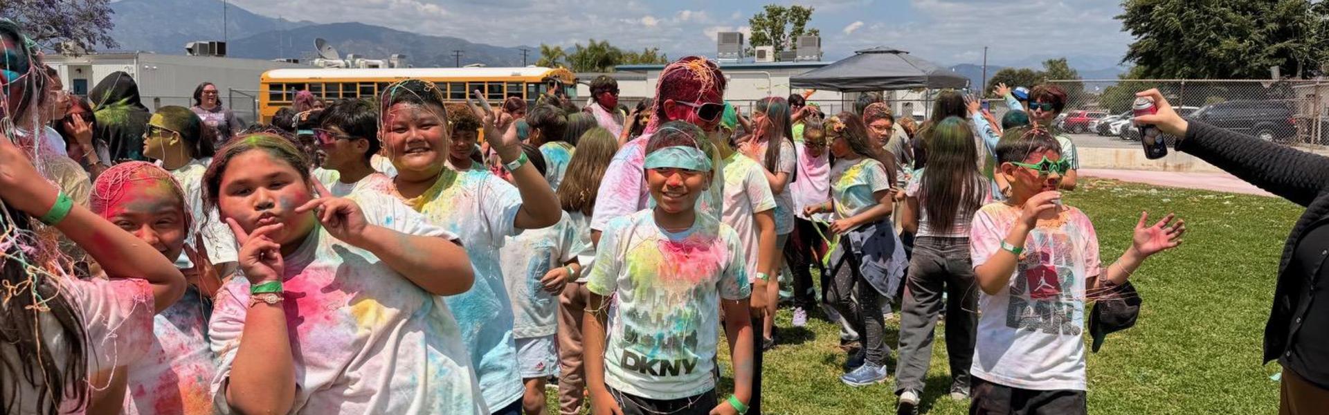 Happy group of children with colorful powders on their clothes posing for the camera.
