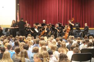 seated students look up at orchestra