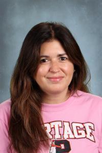 Smiling woman with long brown hair in a pink shirt.