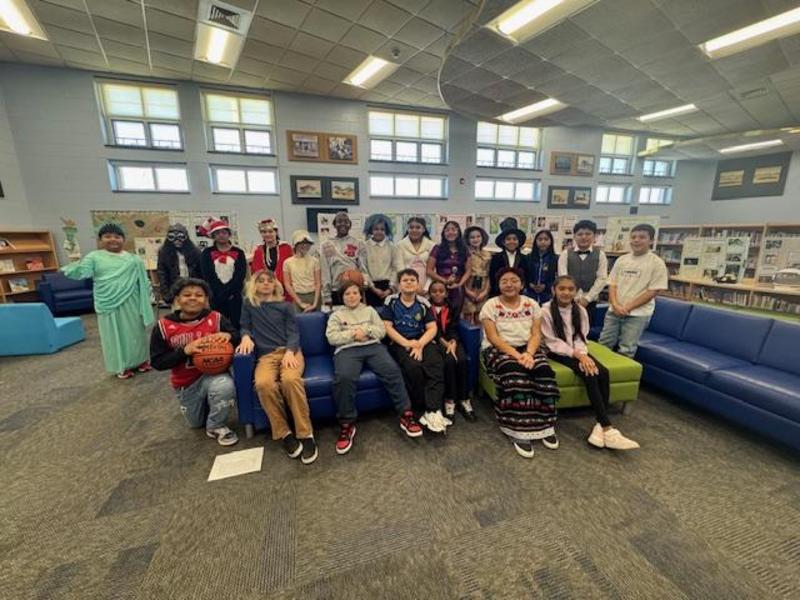 A diverse group of students posing together in a school library setting.