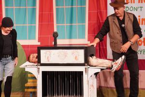 A student lays in a magician's box.