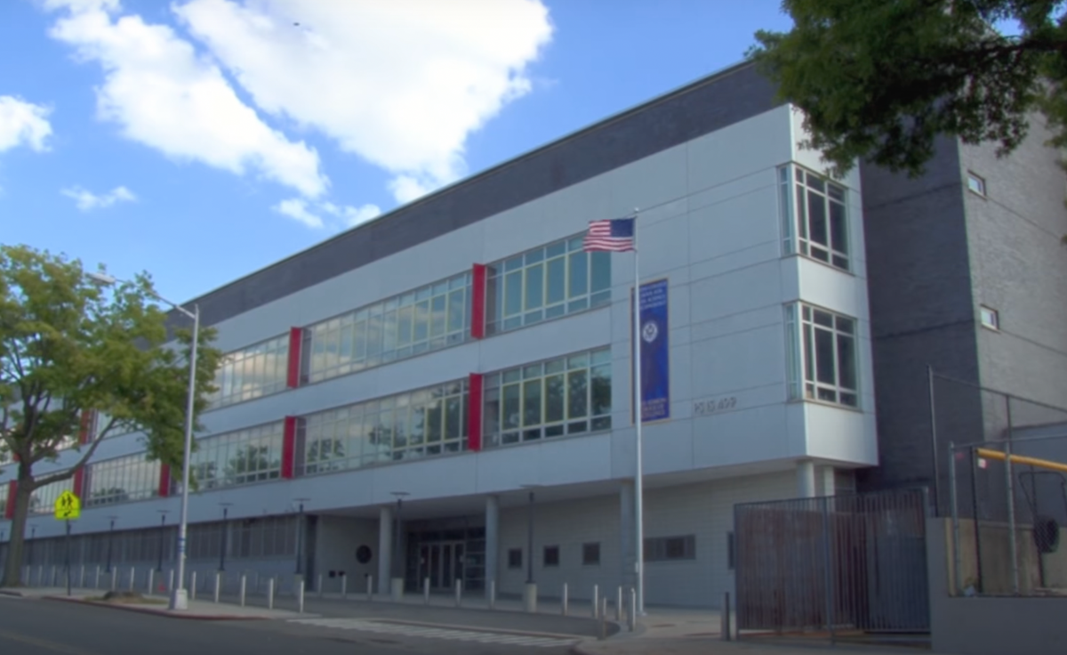 Modern school building with large windows and American flag outside.