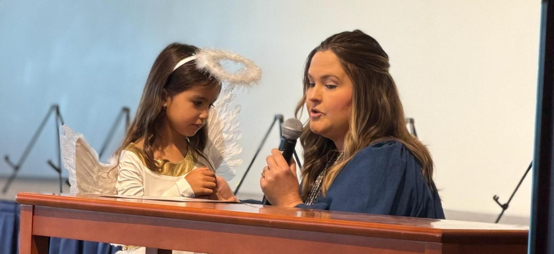 Tk teacher with student presenting about their class saint