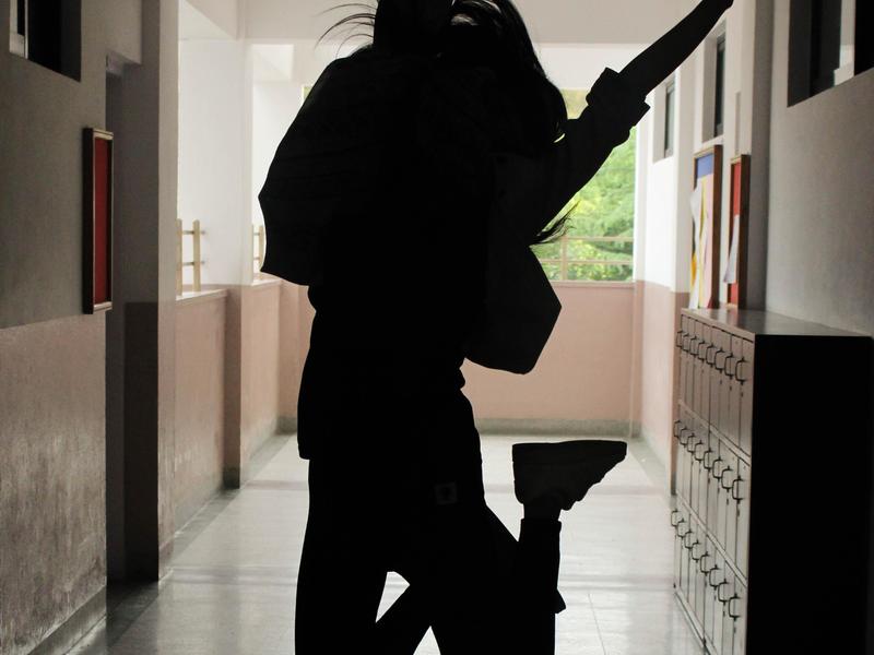 Silhouette of a person jumping in a hallway with sunlight streaming in.