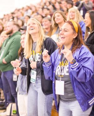 Cheering crowd with women holding pom-poms in a gym.