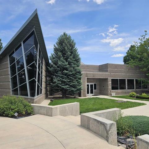 Modern building with angular architecture and a large evergreen tree outside.