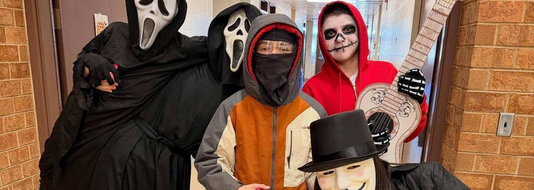 Three individuals in costumes posing indoors, one in a mask and a trench coat.