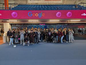 Group of students posing together under a Google sign at an event.