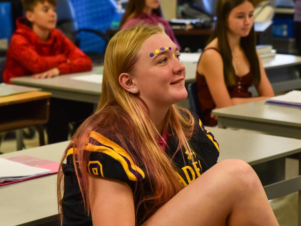 A student wearing face paint and a Pirate's jersey sitting in a classroom.
