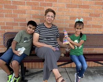 grandma sitting between grandkids on bench in front of brick wall
