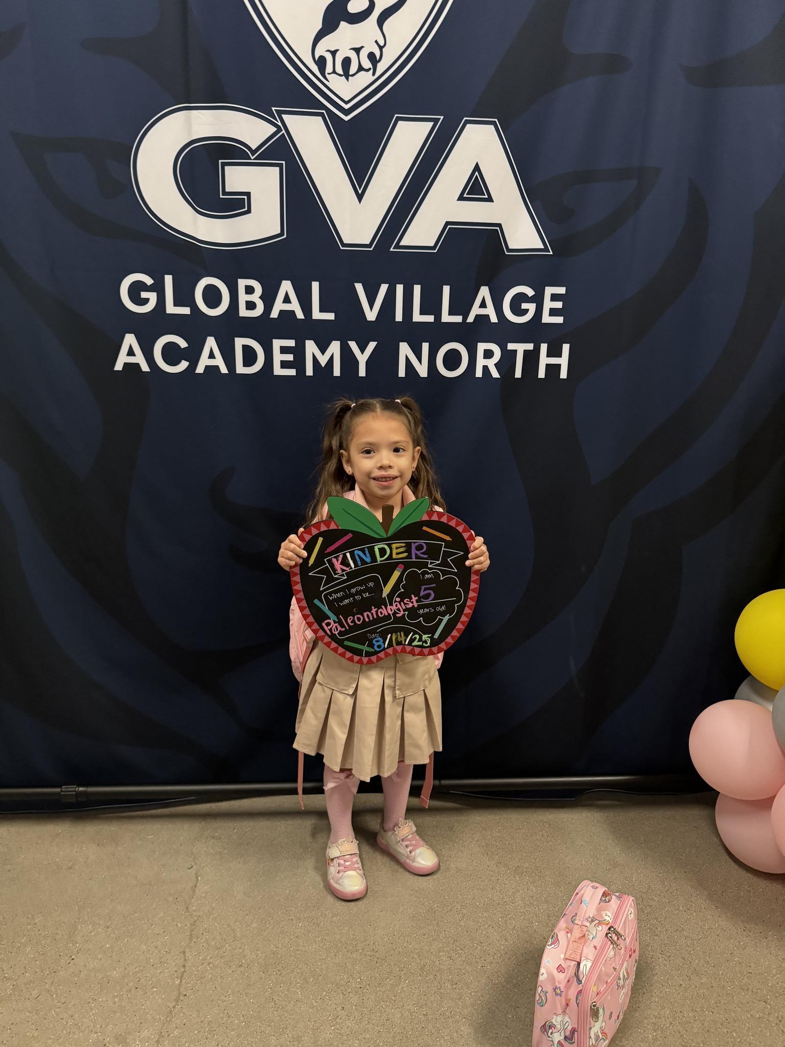 little girl holding first day of kindergarten sign in front of a puma banner