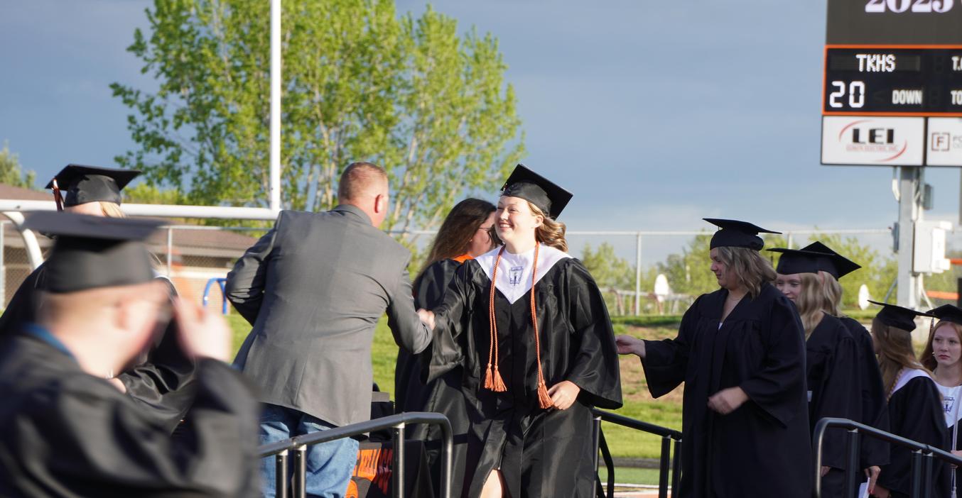 A graduate receives her diploma from one of the TKHS board members.
