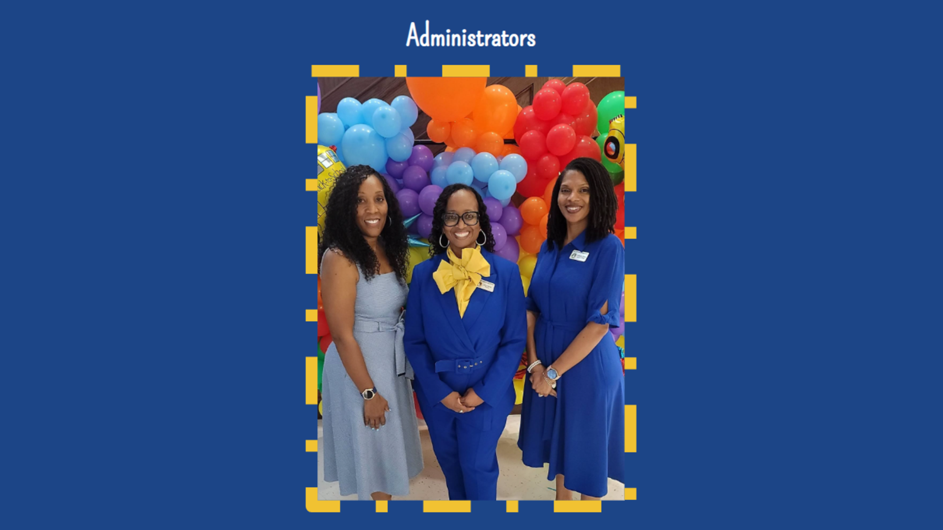 Three administrators smile together in front of colorful balloons.