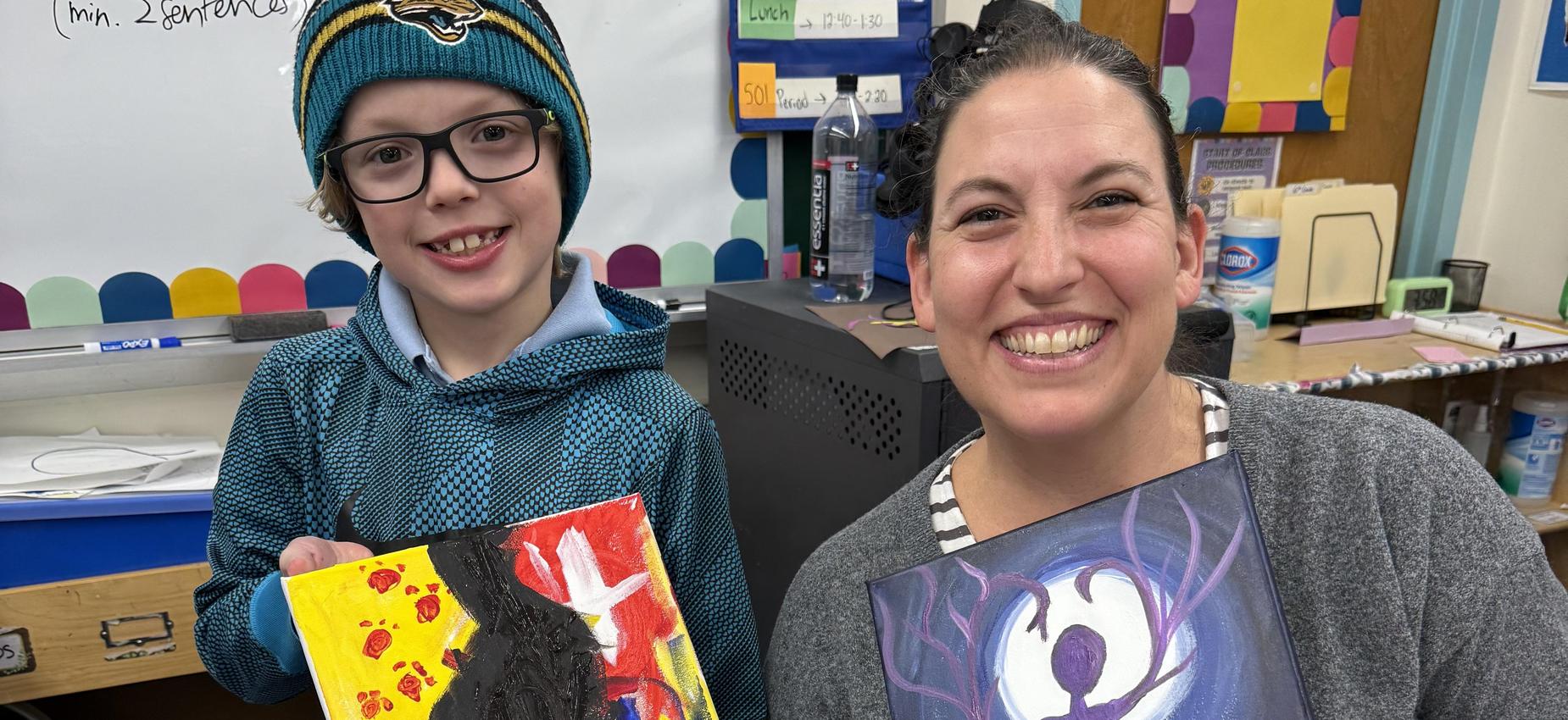 Student and parent displaying their paintings.