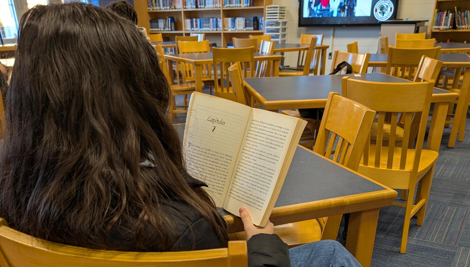 girl reading a book in Spanish in the library