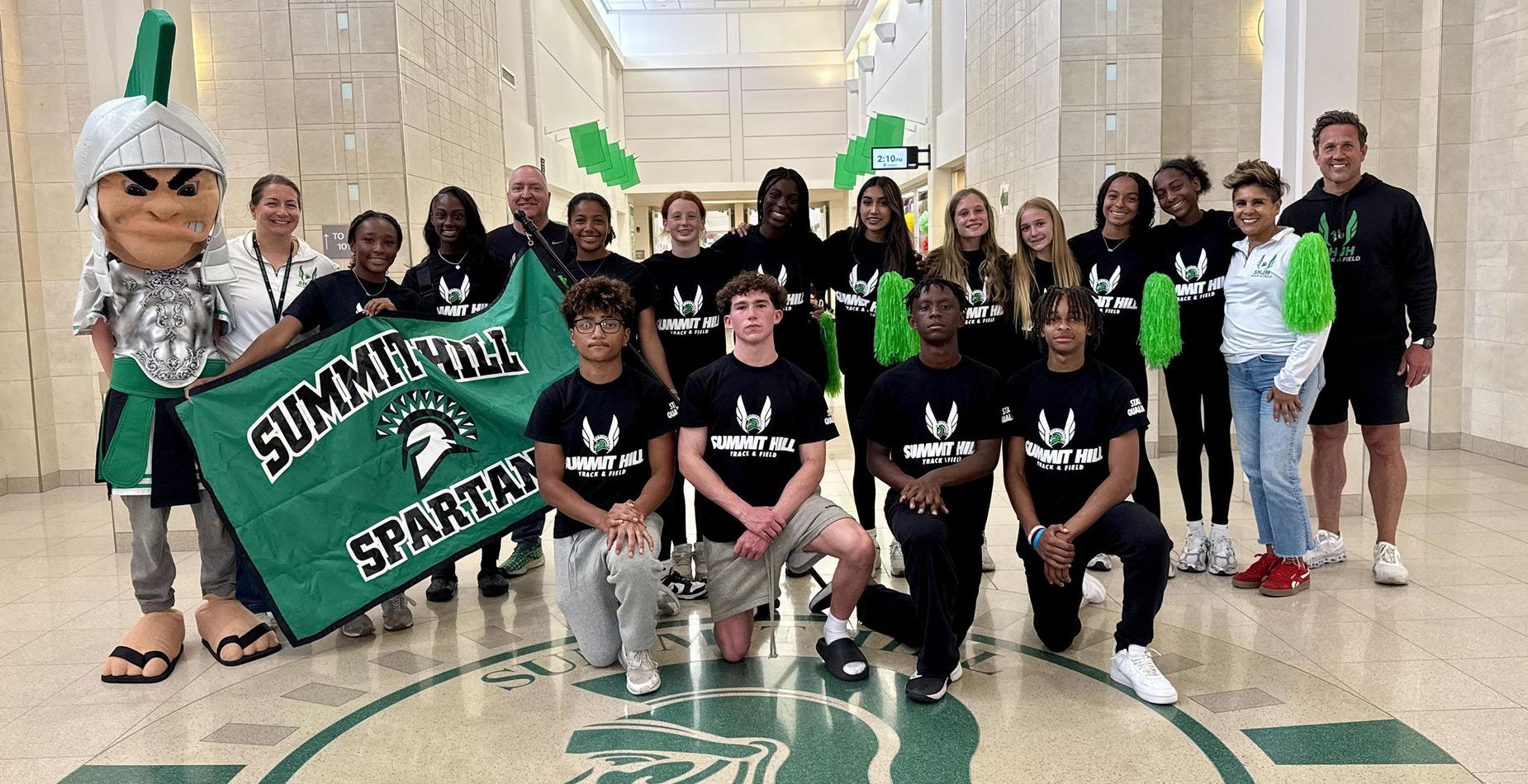 Group photo of the Summit Hill Junior High student-athletes who qualified for the IESA 4A State Track and Field Meet and the team's coaches taken inside the school's main entrance.