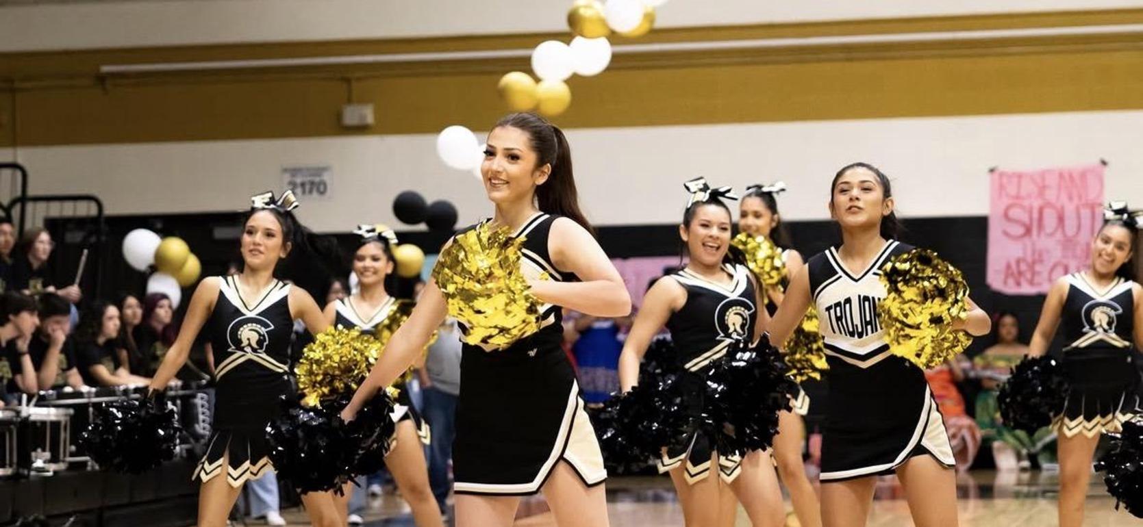 Cheerleaders performing with pom-poms at a sporting event.
