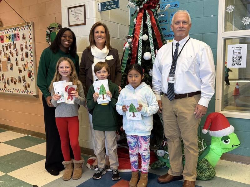 Three adults dressed as Dr. Seuss characters&mdash;Thing 1, Thing 2, and the Cat in the Hat&mdash;pose together in a decorated library or book fair area.