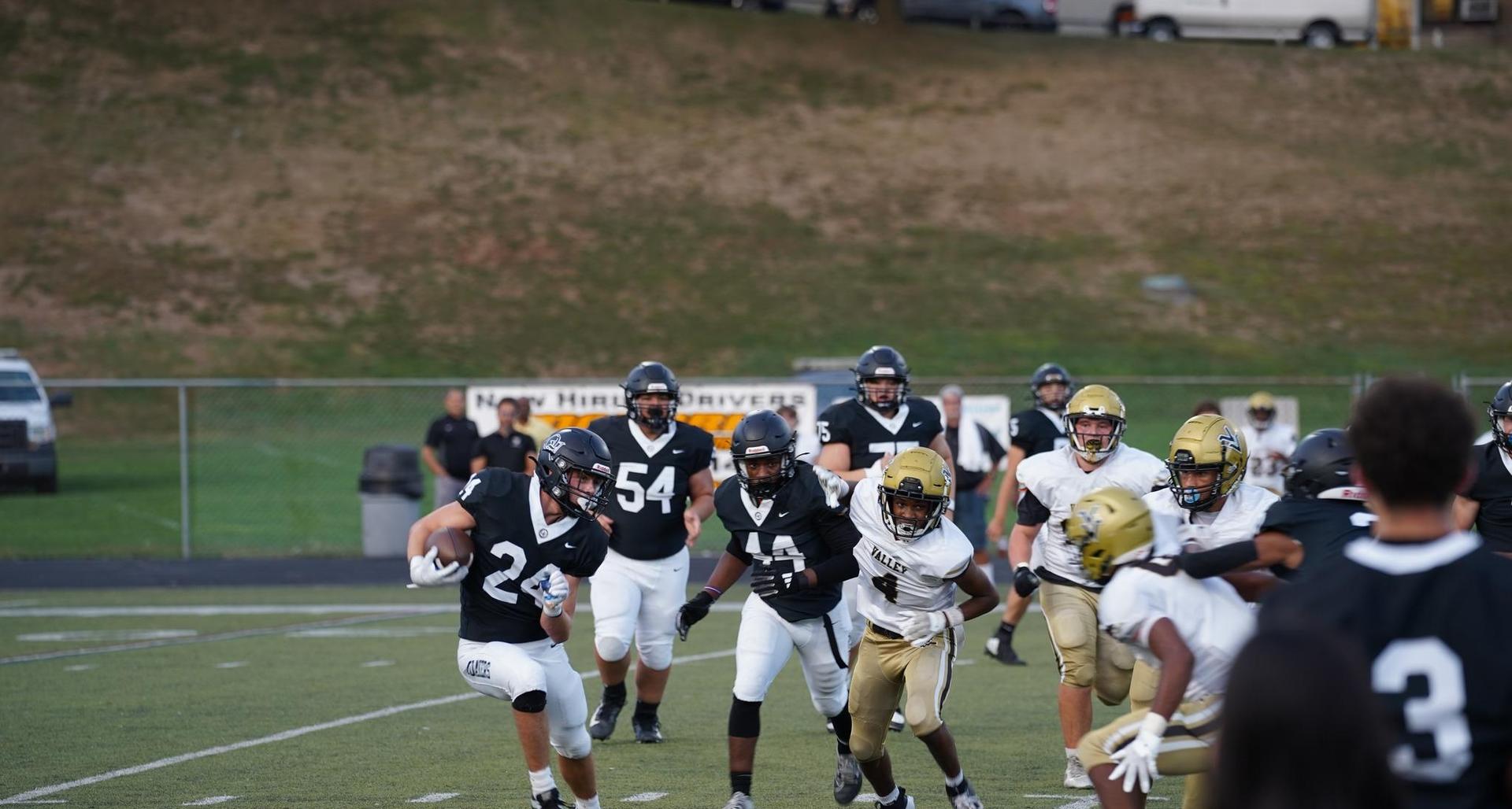 A football player in black evades defenders during a game on the field.