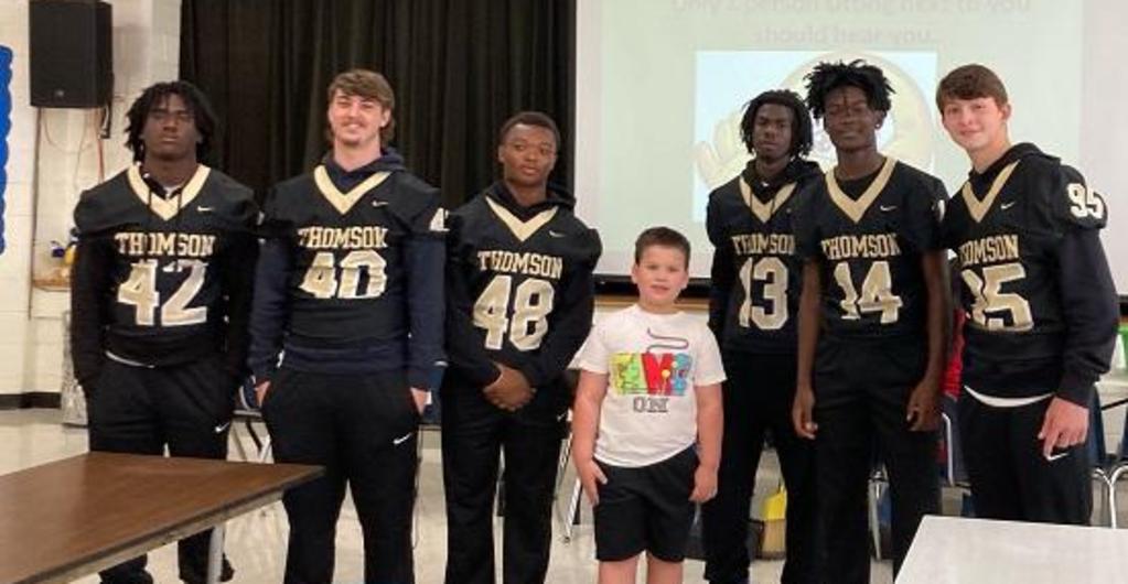 High school football players singing happy birthday to third grader