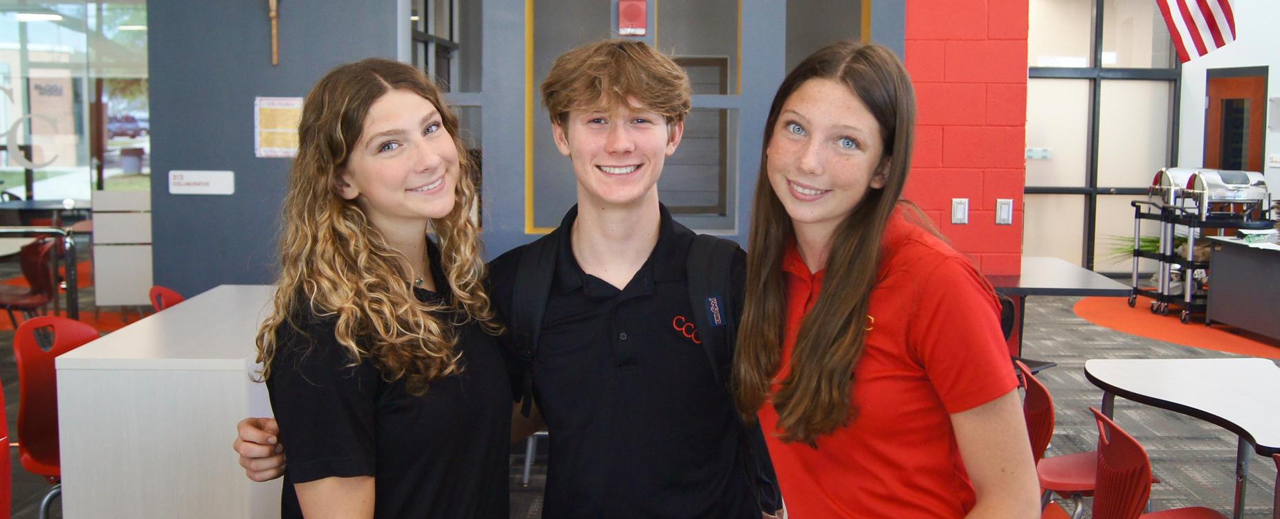 three students smiling in black and red polos