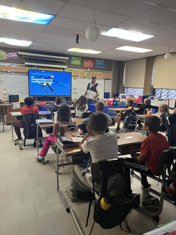 man stands in front of class of 4th graders speaking