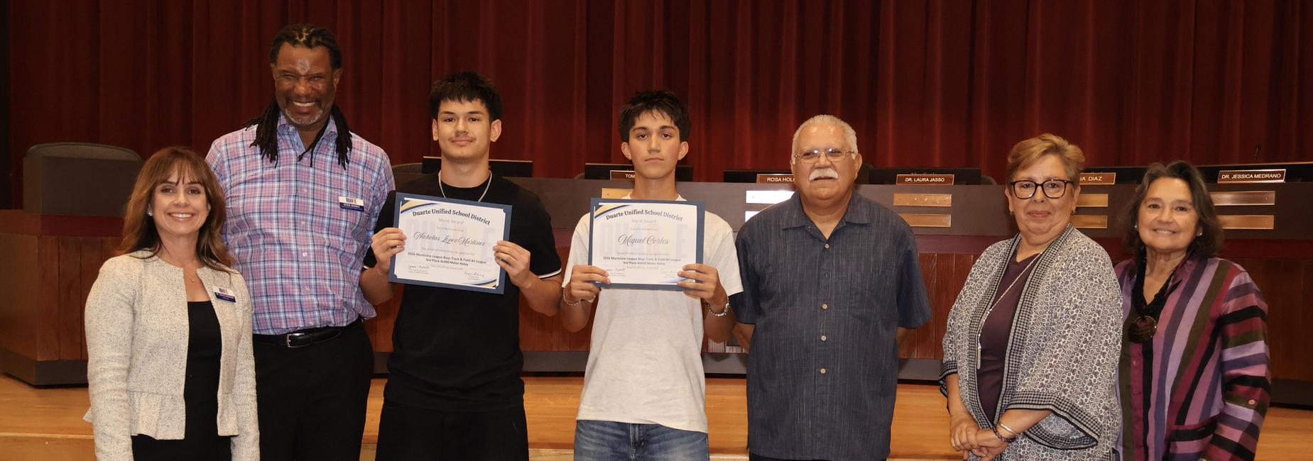 Group of people posing with certificates on a stage.