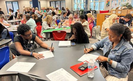 Three women focused on their work at a table in a crowded library space.