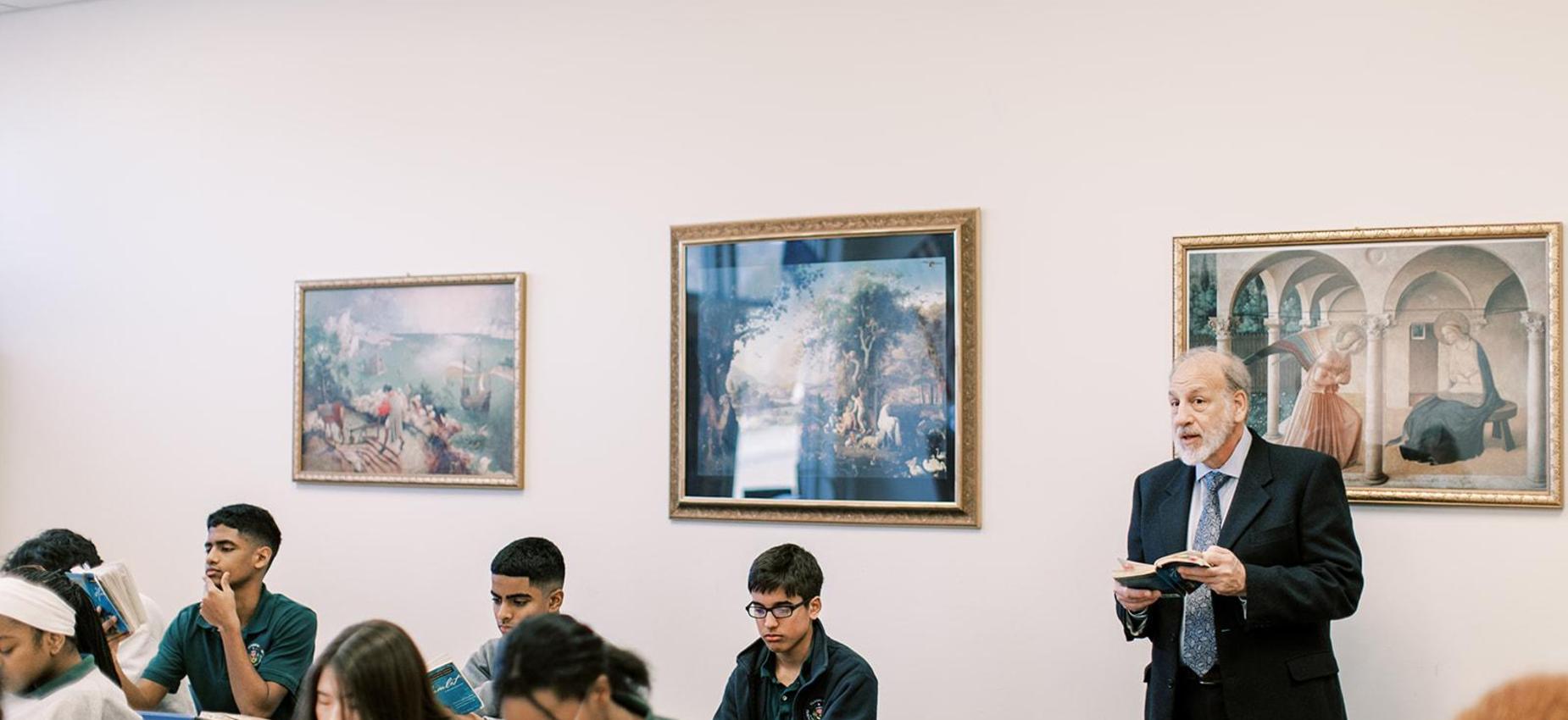 Teacher reads aloud to students in a classroom lined with classic paintings
