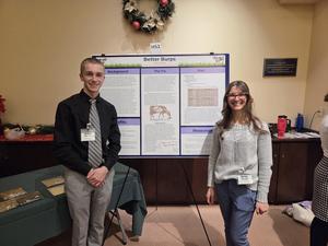 student and teacher standing in front of poster about cows