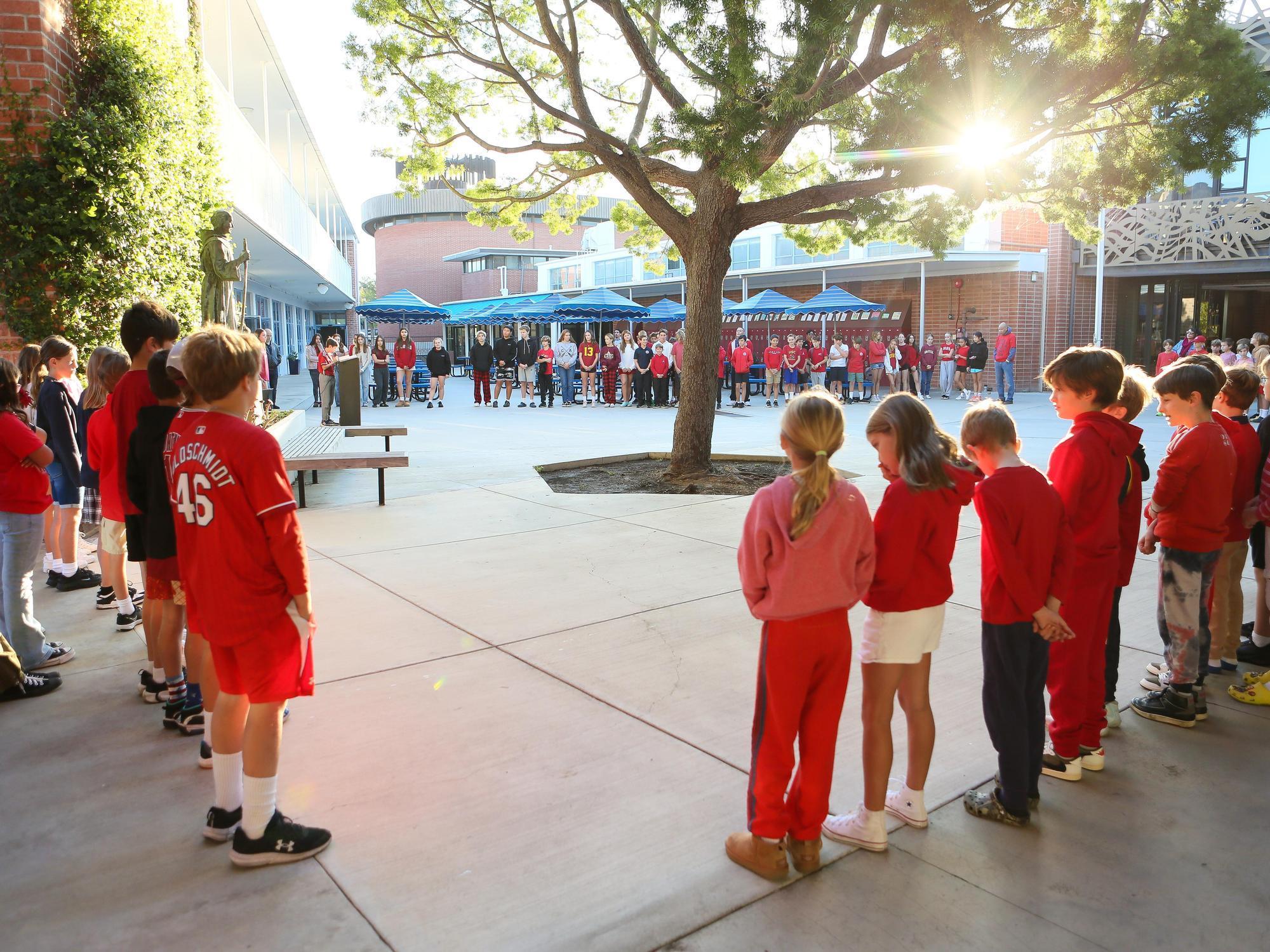 Students gathered in a circle outside a school, engaging in a group activity.