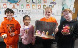 Four students hold up their gourd projects.