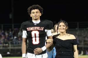 A young man in a football jersey escorts a girl in an elegant black dress.