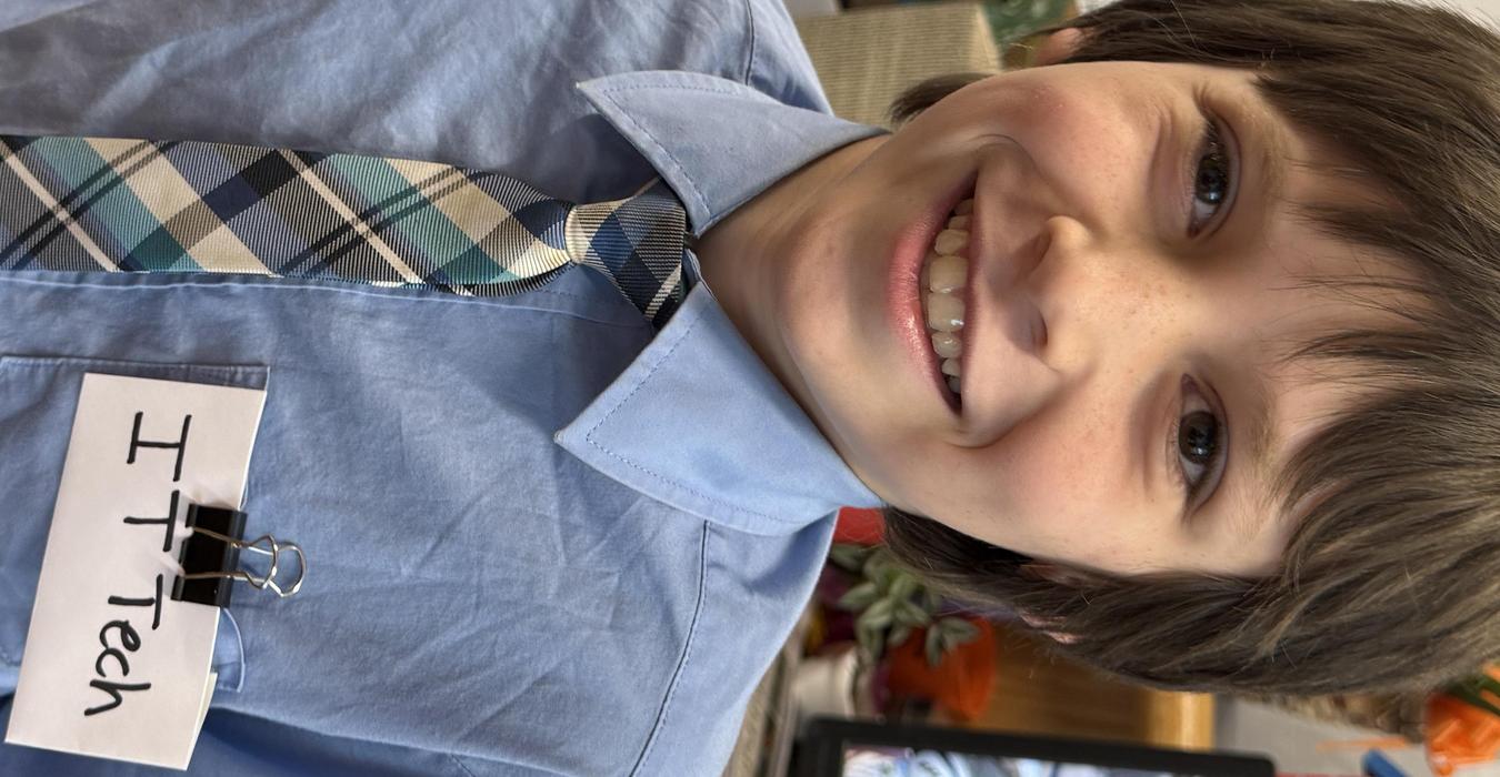 Boy wearing a blue shirt and tie with an IT Tech name tag.
