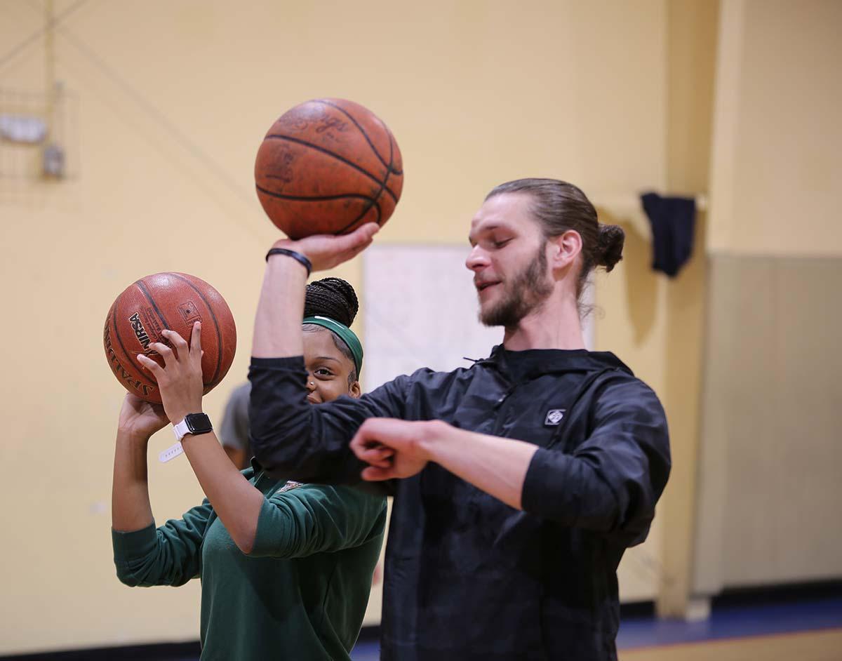 Horizon Science Academy Cleveland Elementary Student shooting a basketball with a teacher in the gym