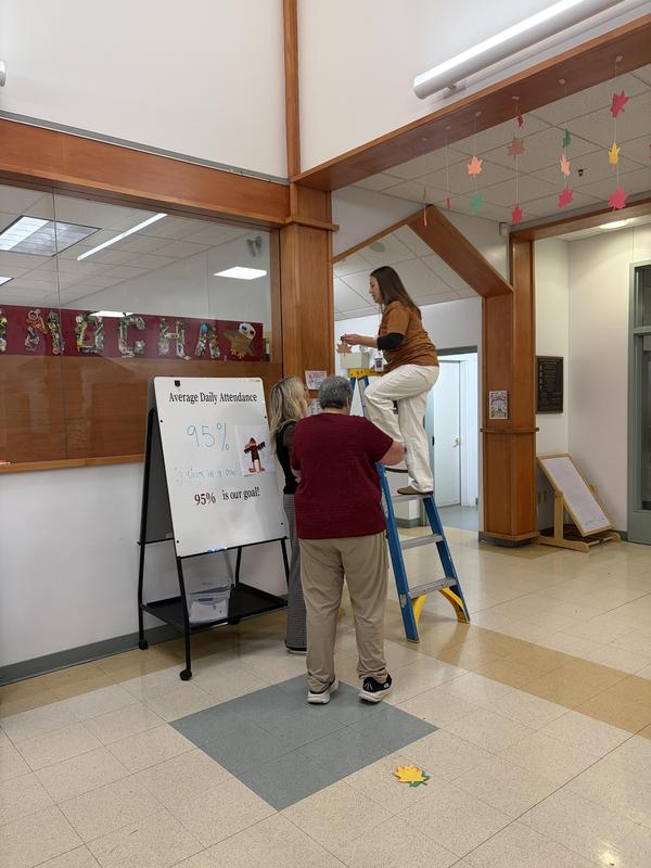 A group working together, one on a ladder adjusting a sign.