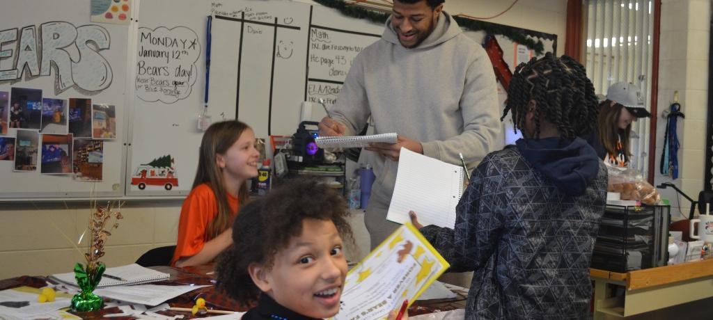 football player signs autographs for three students