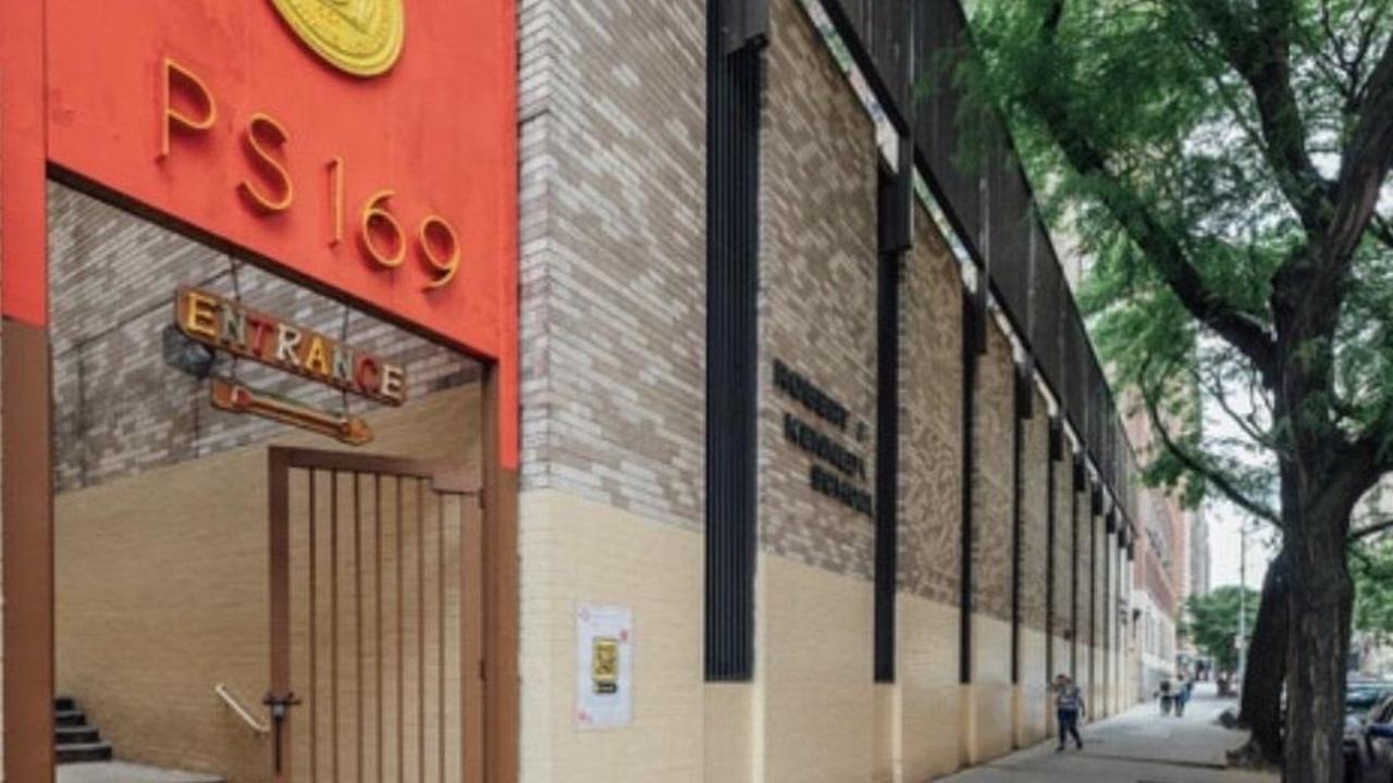 Exterior view of PS 169 school entrance with large red sign and nearby tree.
