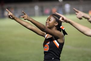 A cheerleader points enthusiastically while performing on the field.