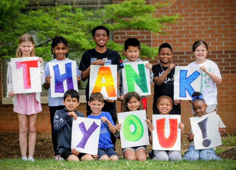 Kids holding up signs that say thank you.