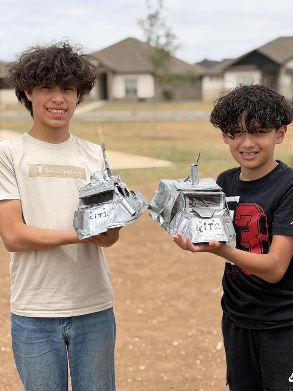 Two students holding up storm chaser invention