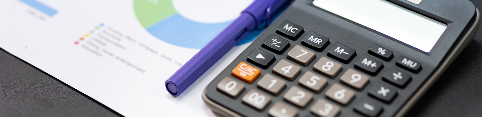 close-up photo of calculator, purple pen, and sheet with charts