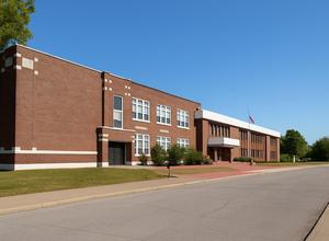 Brick school building with a clear blue sky and grassy area.