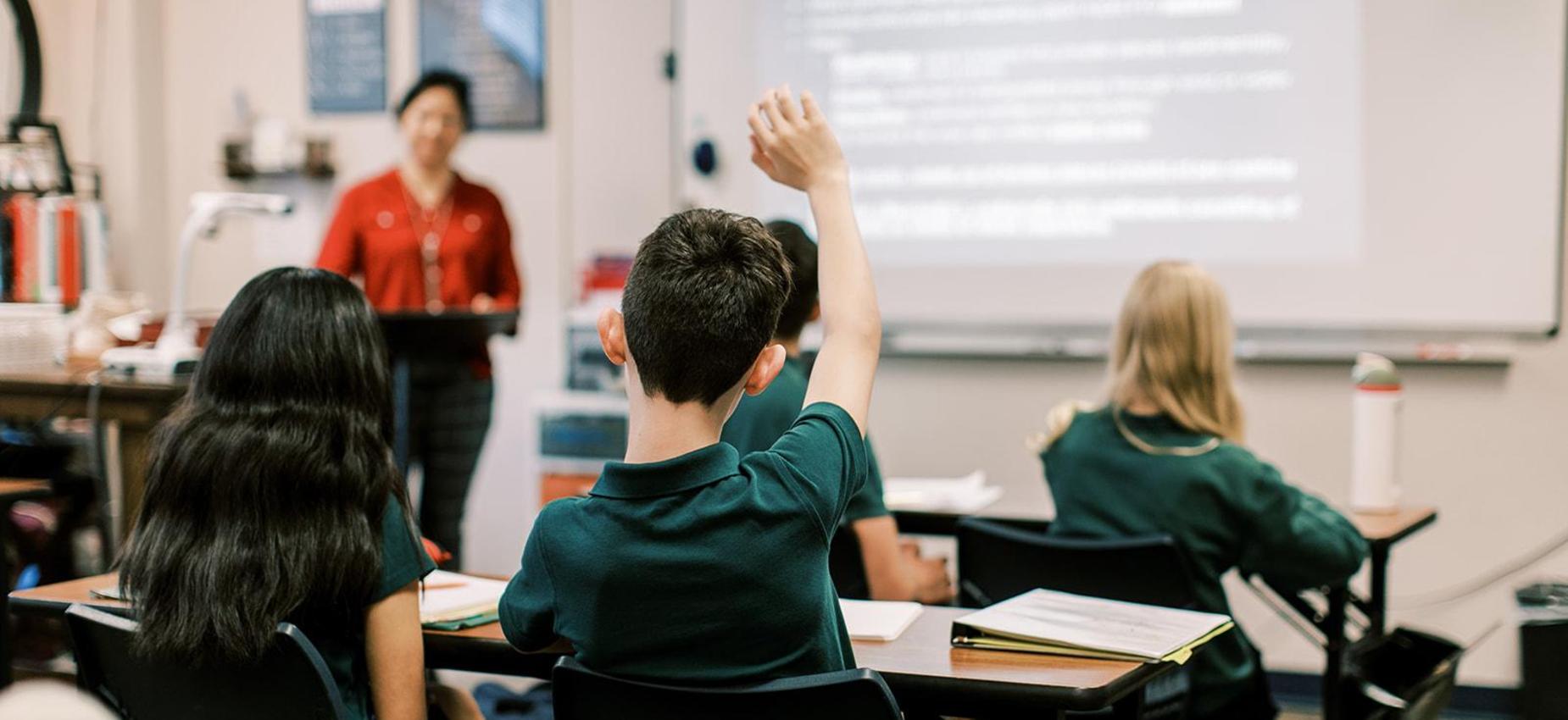 Students raise their hands as the teacher calls on them