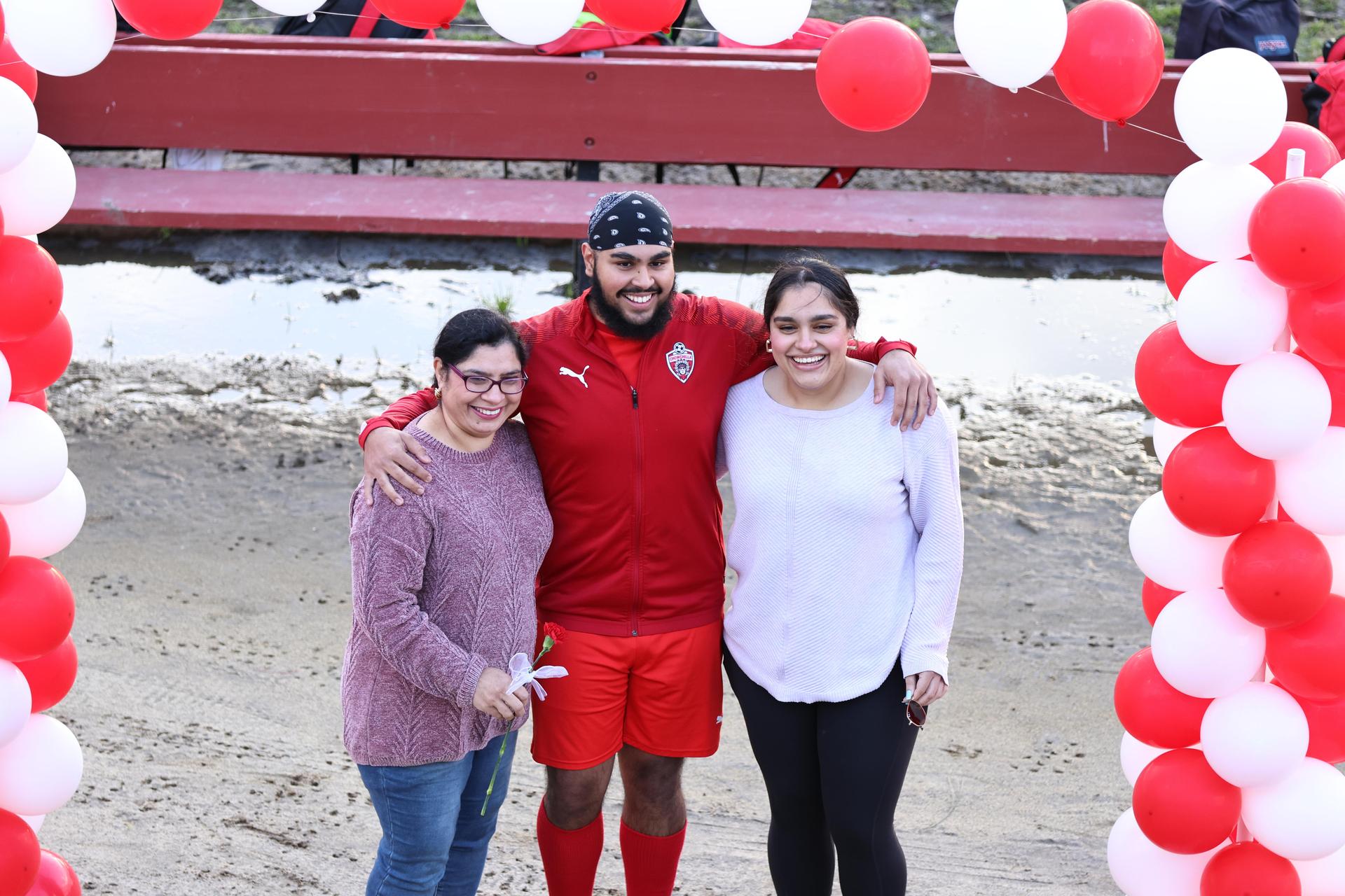 seniors and their escorts posing beneath a balloon arch