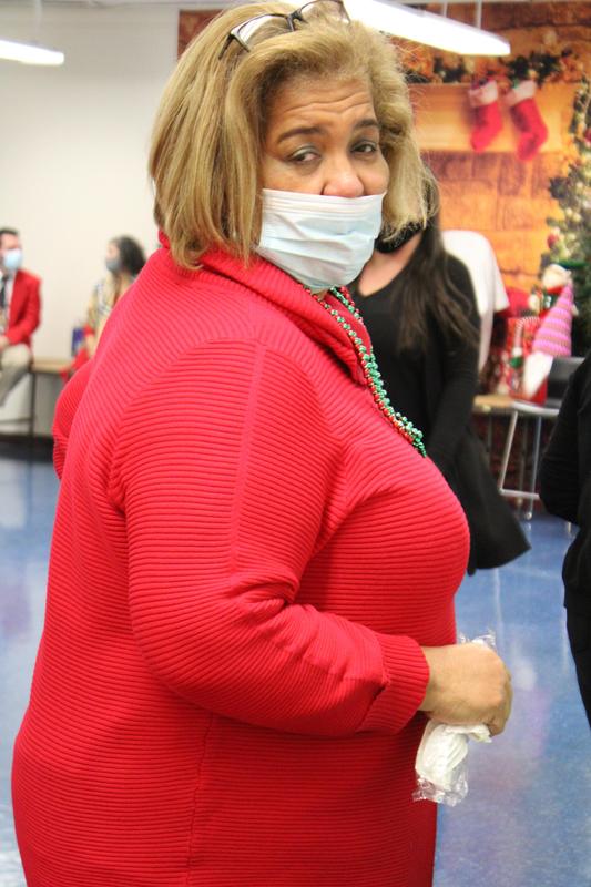 Woman in mask and red sweater looking back at camera