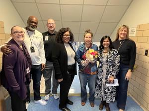 Julie Rossi holds flowers surrounded by district and school leaders