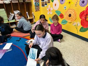a seventh grade girl read her Gadol picture book to a kindergarten student.