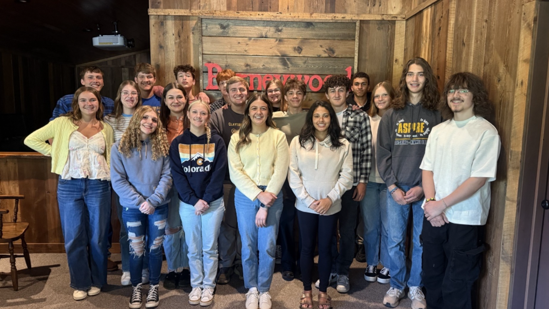 Group of young adults posing together in a rustic room.