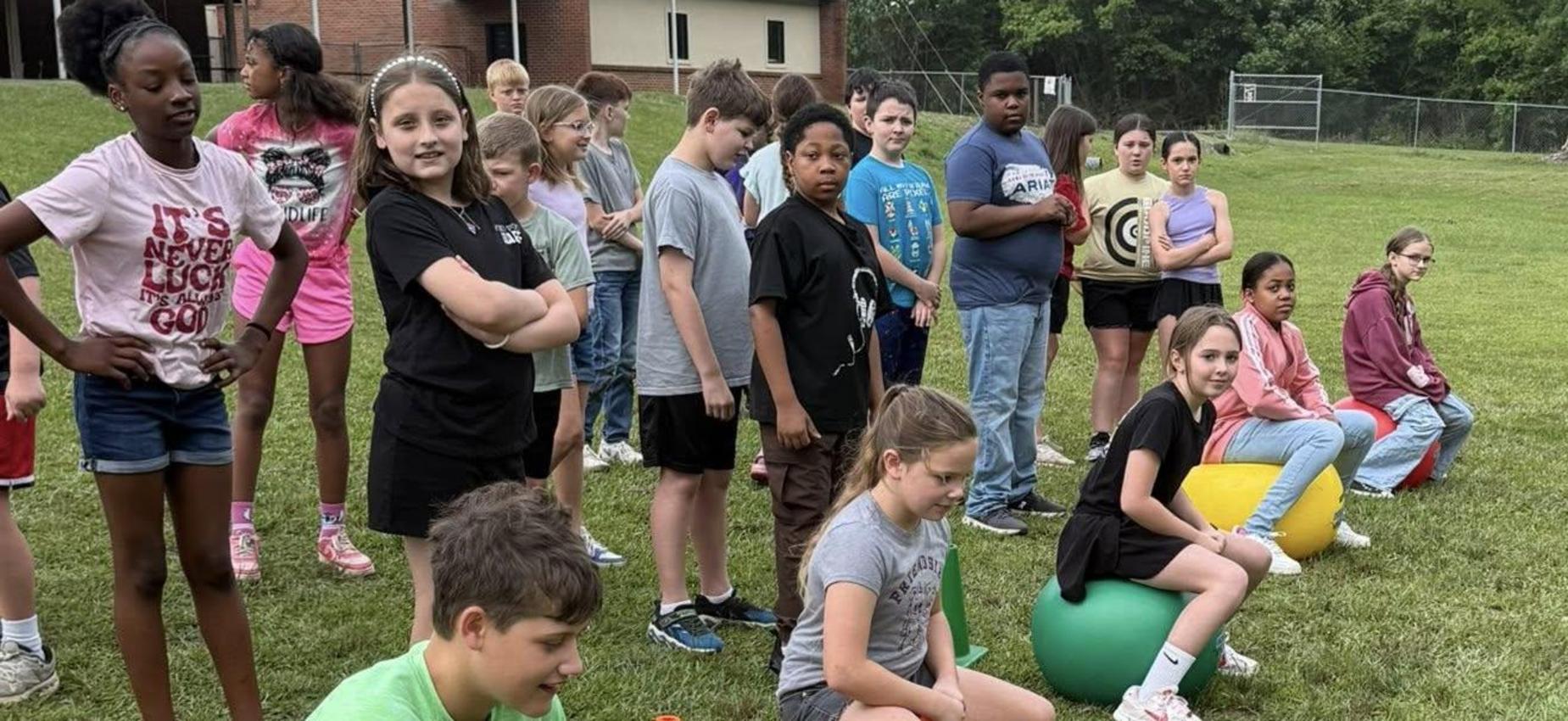 Children ready for a bouncing activity on colored exercise balls.
